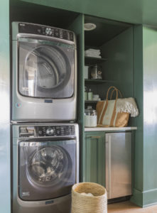 hidden laundry cabinet in green cabinetry